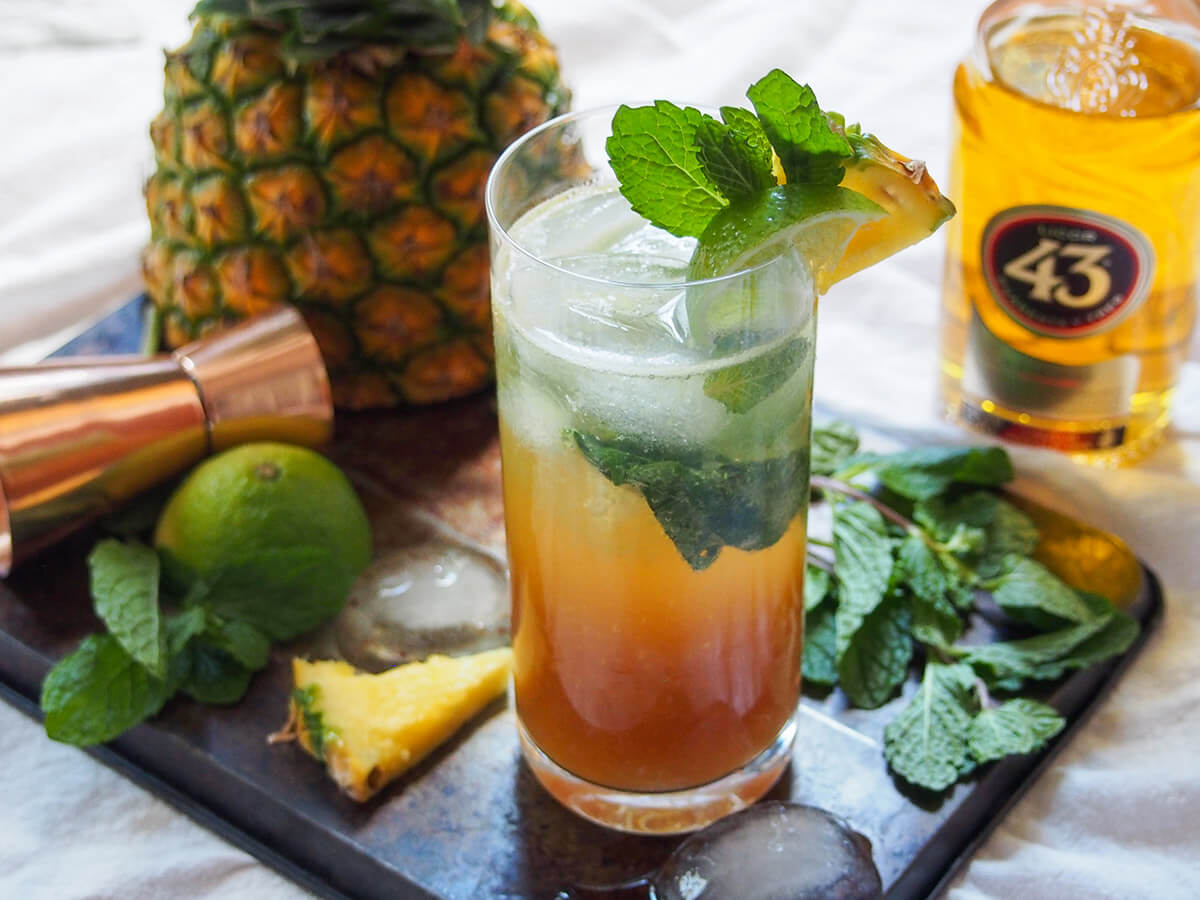 43 pineapple mojito with bottle of licor 43 to one side and pineapple behind on other