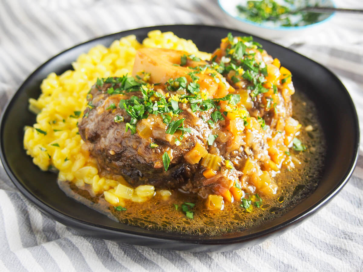 plate of beef osso buco on top of saffron risotto