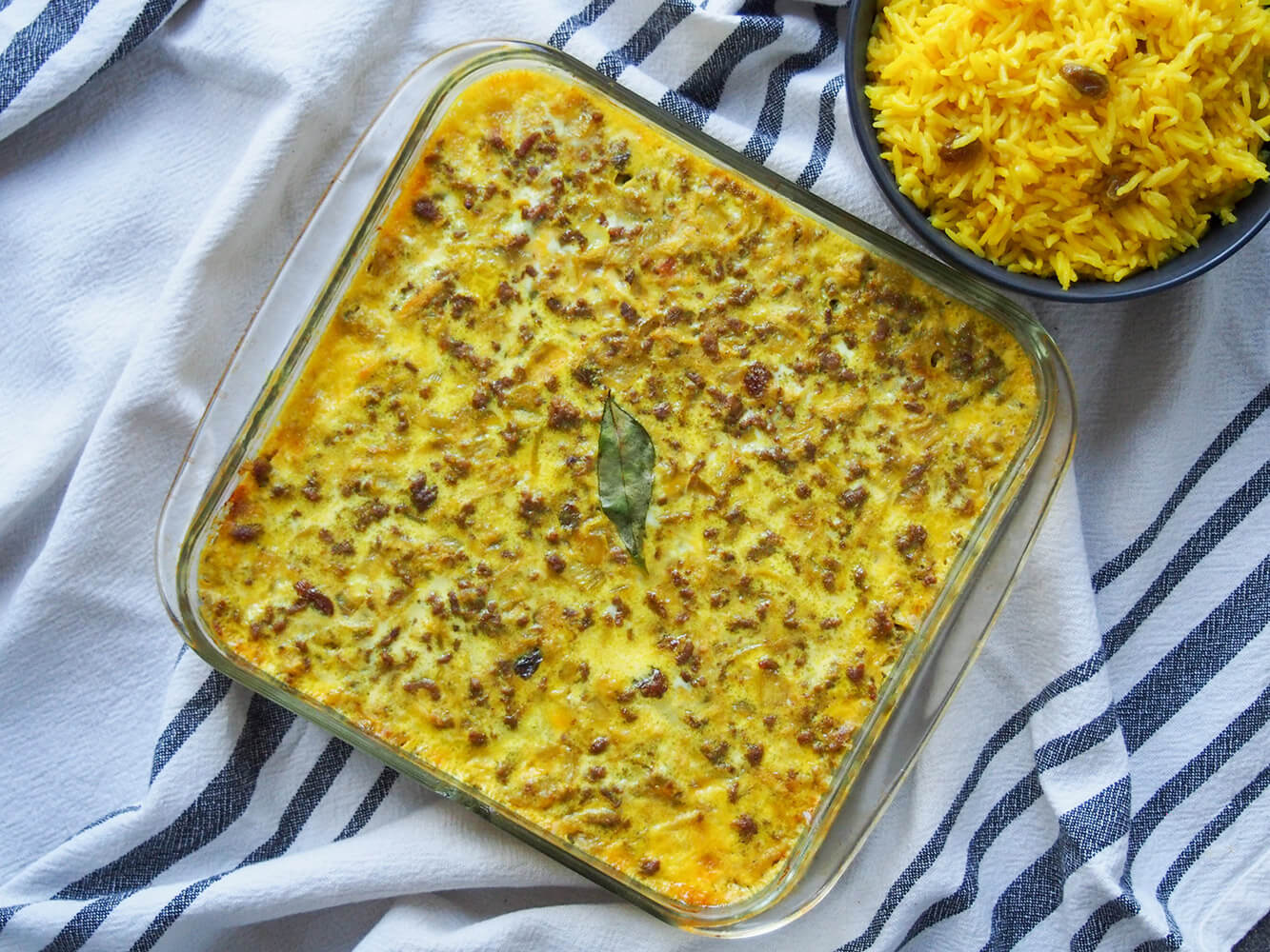 whole bobotie in baking dish with rice to side