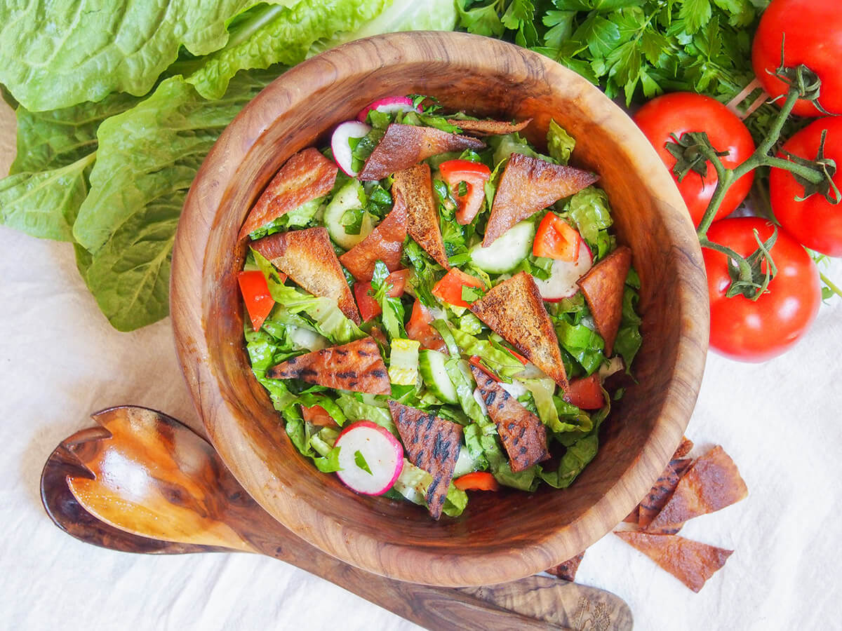 bowl of fattoush salad from overhead with tomatoes to side and lettuce to other