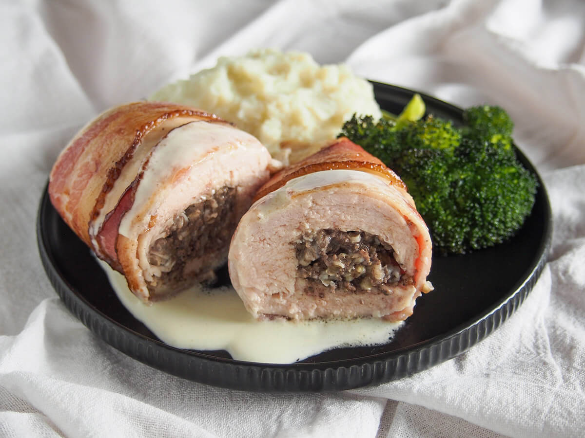 black plate with haggis stuffed chicken Balmoral with mashed potato and broccoli behind