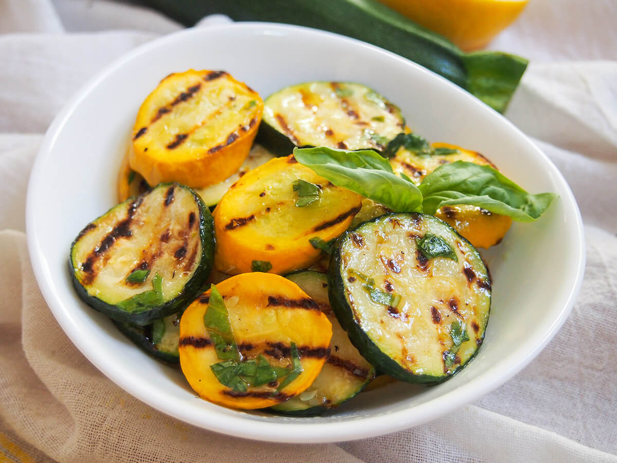 bowl of marinated grilled zucchini and summer squash with basil garnish