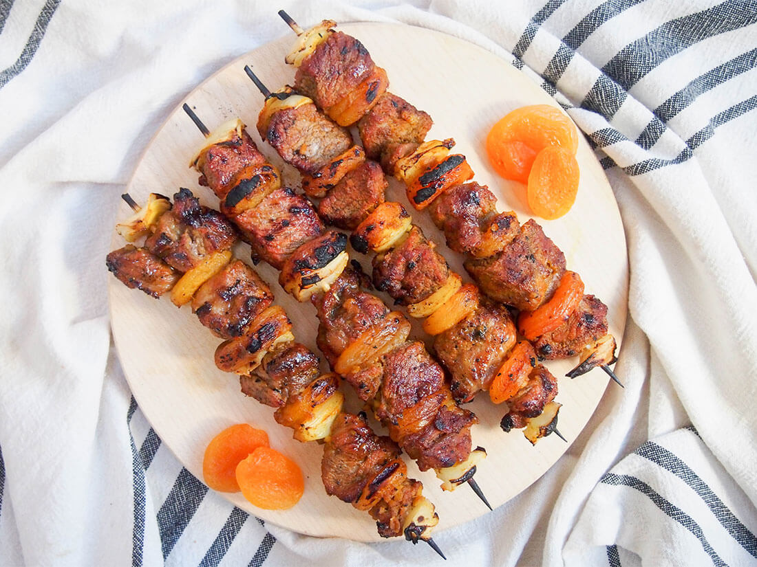 Sosaties (South African lamb and apricot kebabs) on board with apricots to either side