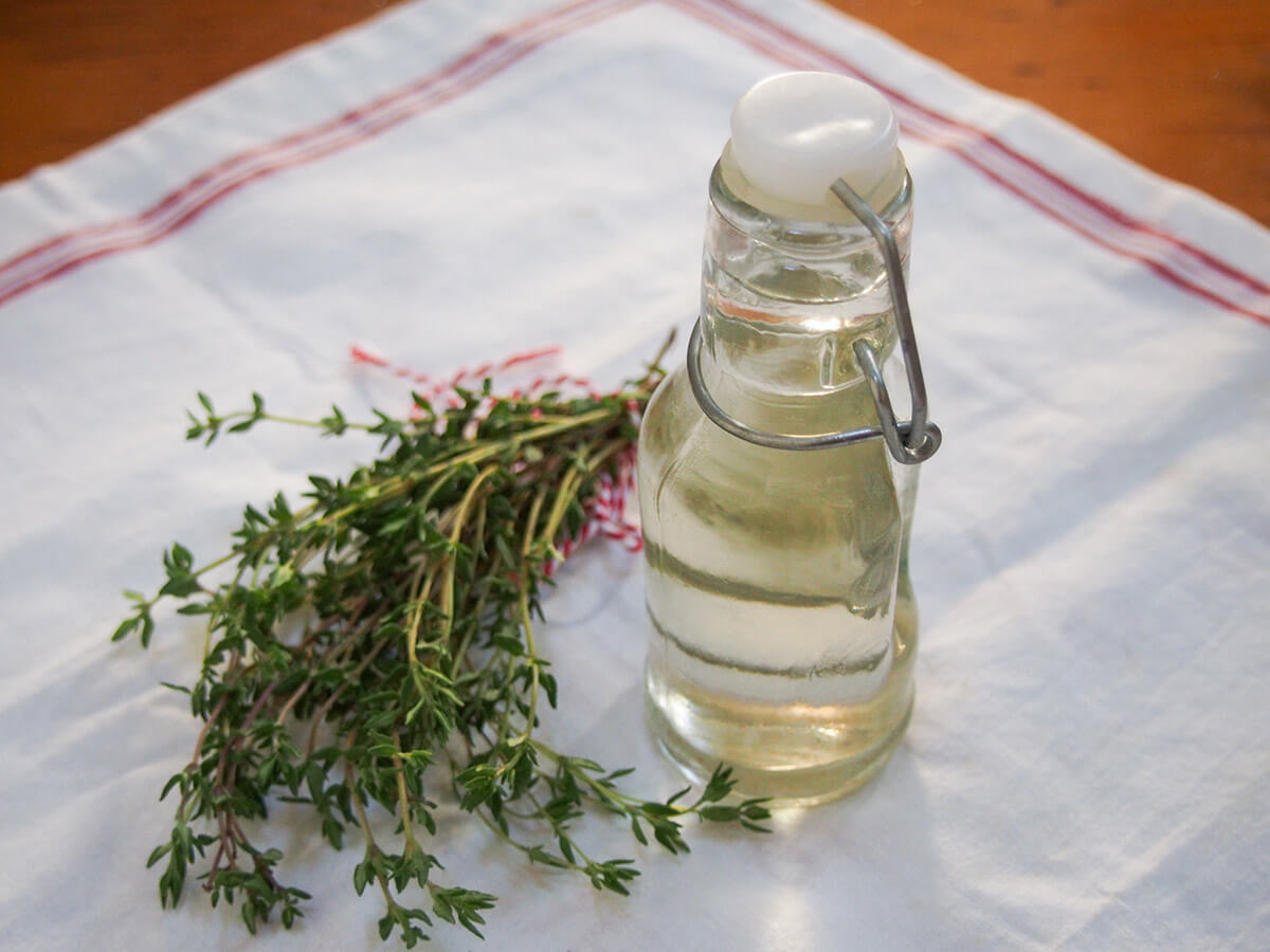 bunch of thyme and bottle of thyme simple syrup next to each other on cloth