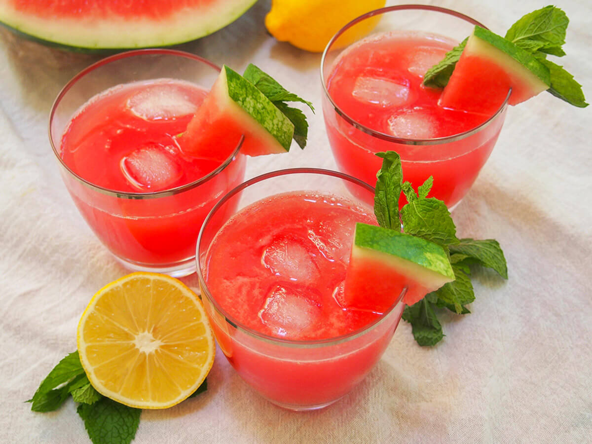 three glasses of watermelon lemonade (or watermelon mint lemonade) with half lemon to side