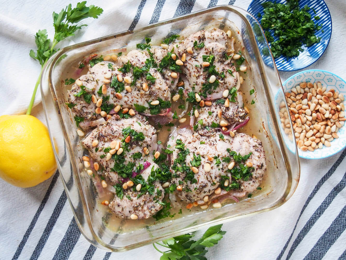 baking dish with za'atar chicken with lemon, parsley and pine nuts to side